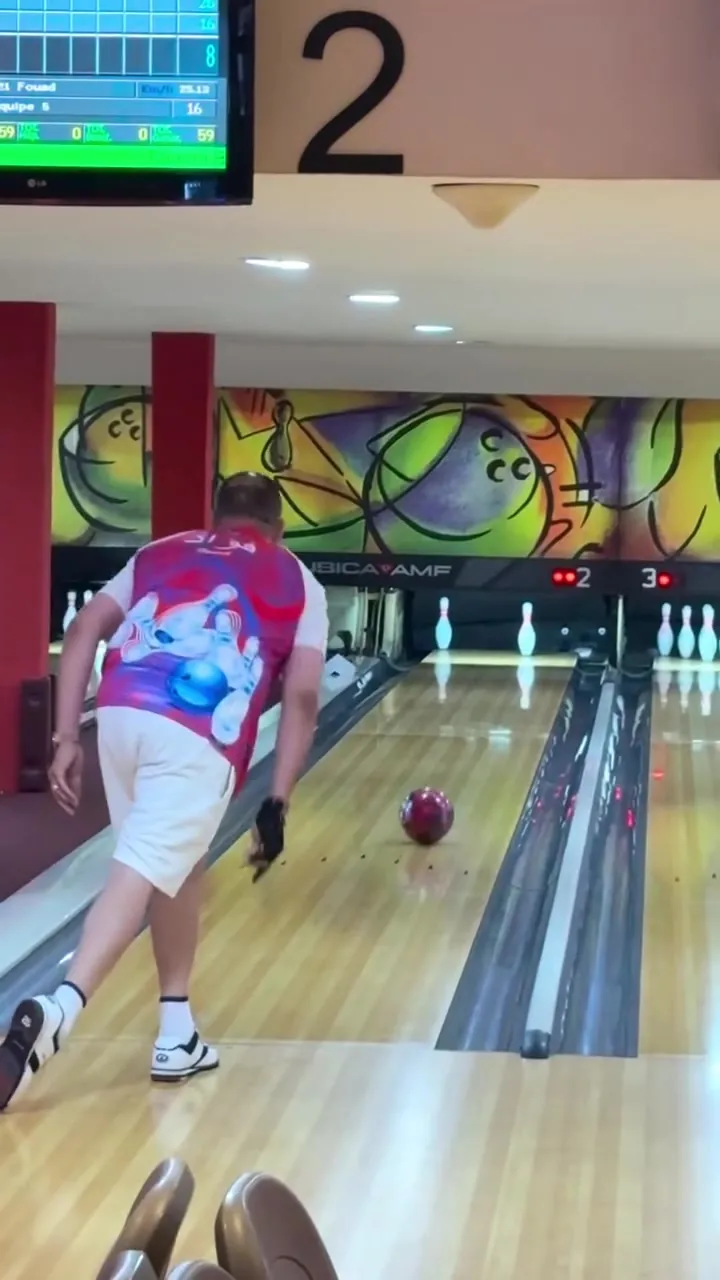 Un joueur en maillot coloré suit sa boule qui roule sur la piste 2