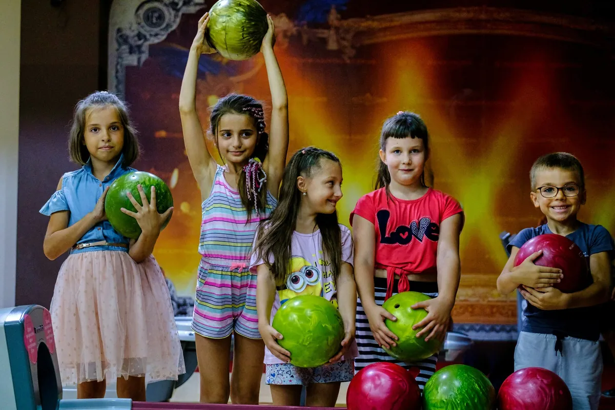 Children holding bowling balls at a birthday party