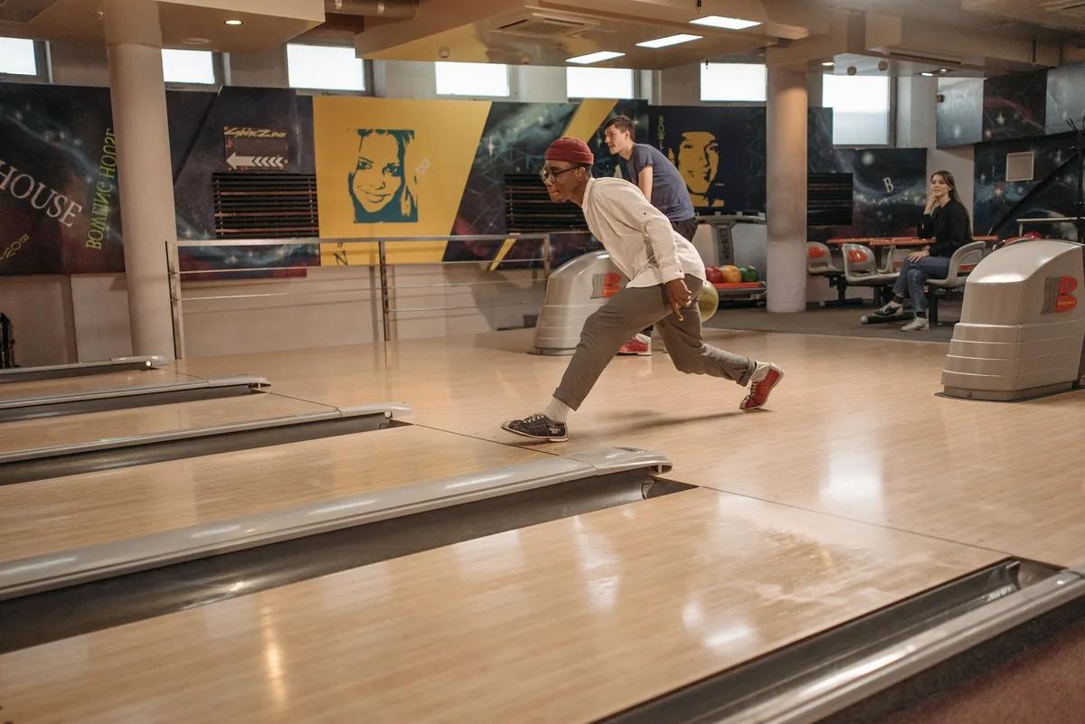 Young man rolling his bowling ball down the lane in a modern bowling centre