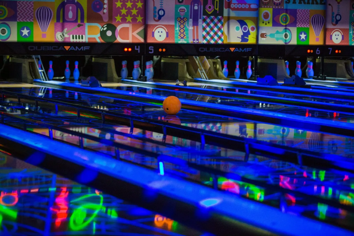 Bowling lanes under black light and neon during an evening session
