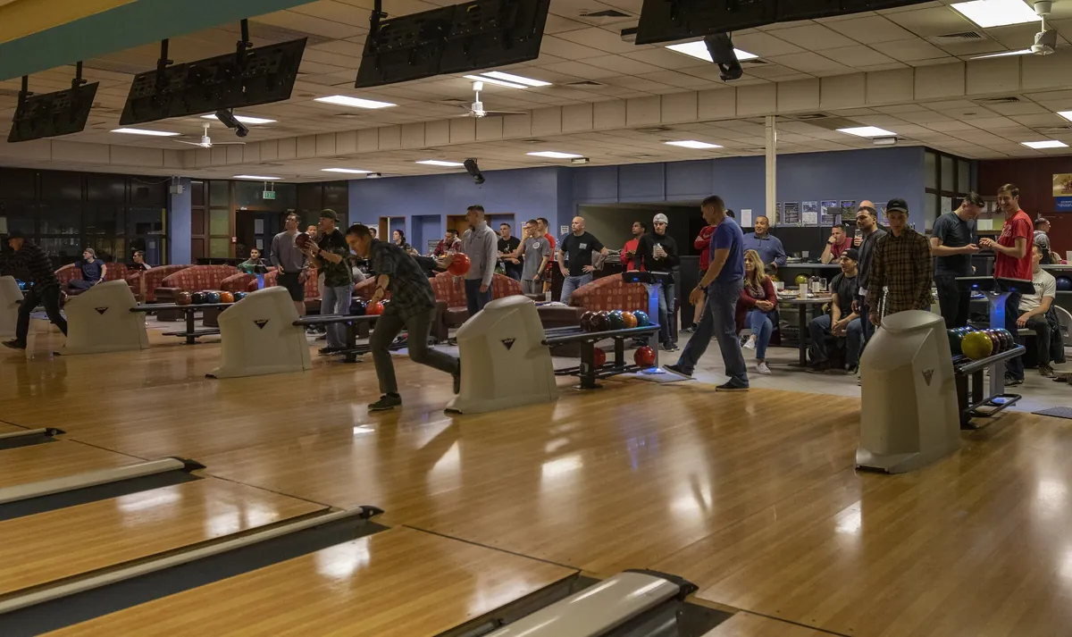 Bowling league night: several teams bowling on neighbouring lanes beneath the score screens