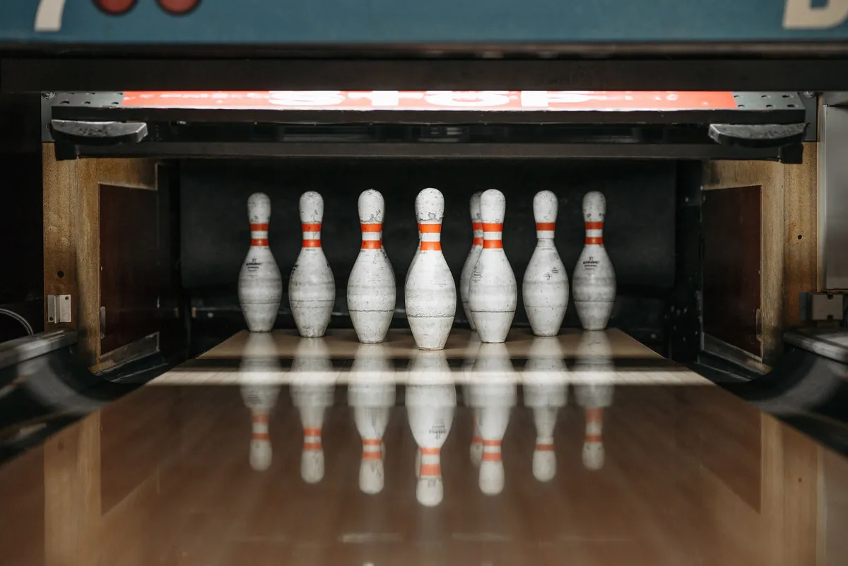 Pins lined up on the pin deck at the end of a bowling lane, beneath the pinsetter