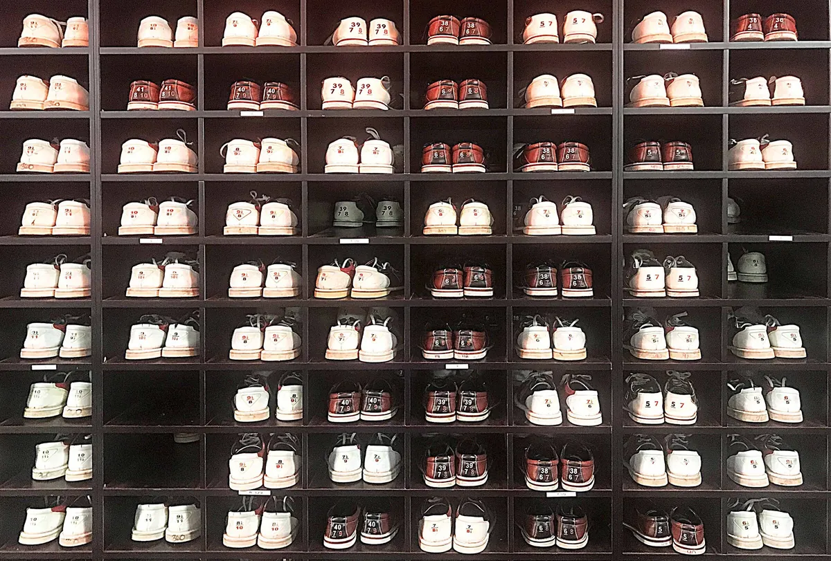 Racks of rental bowling shoes arranged by size at the front desk of a bowling centre