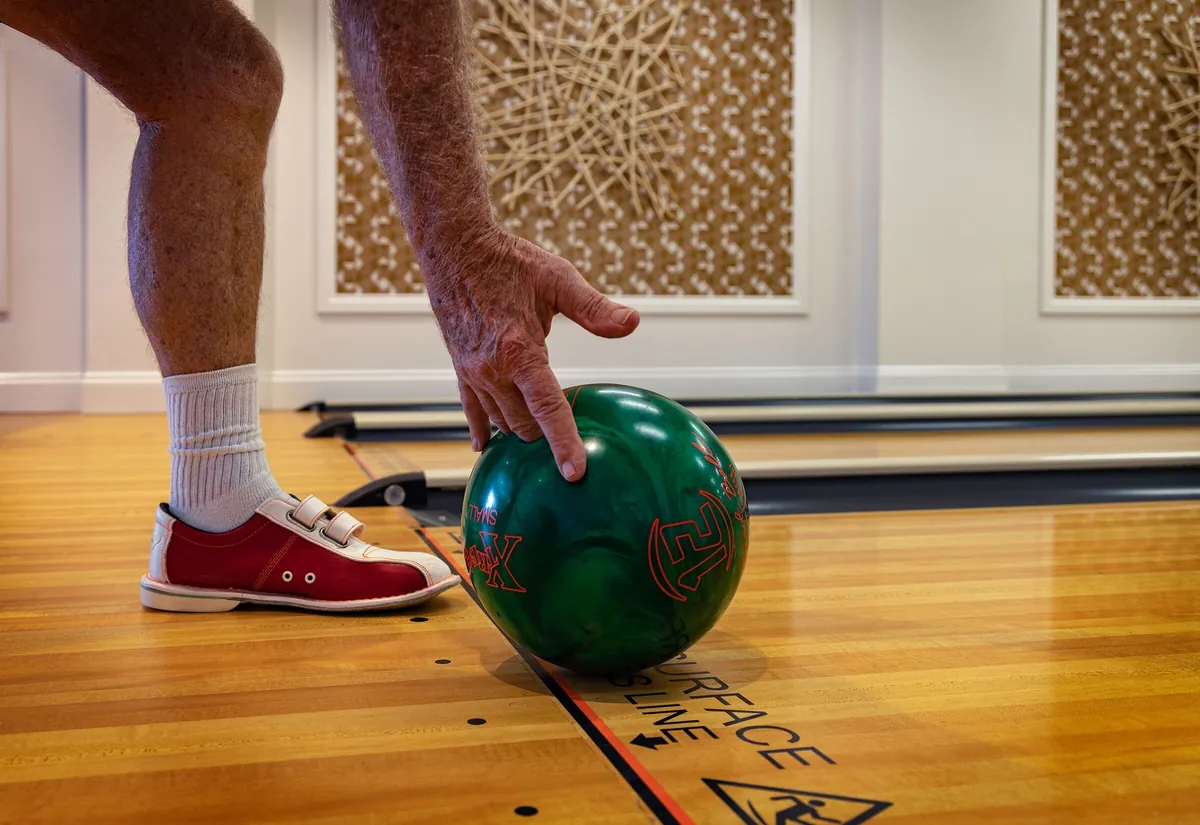 A bowler's foot just behind the foul line as the ball is set down on the lane