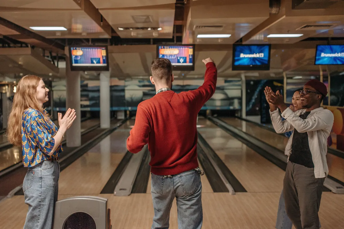 Colleagues cheering and celebrating a strike together during a group bowling outing