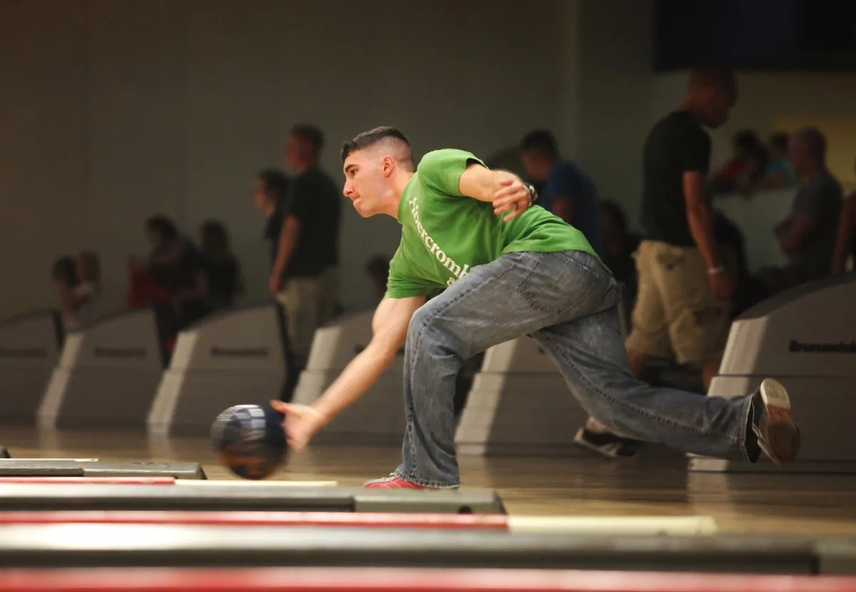 Bowler in the final slide, arm extended, releasing the ball right at the foul line