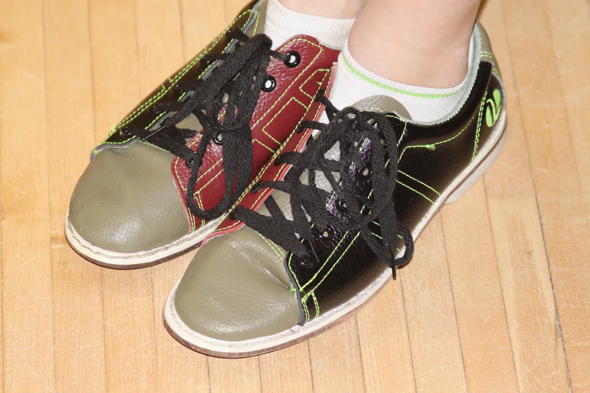 Paire de chaussures de bowling personnelles portées sur le parquet d'une piste
